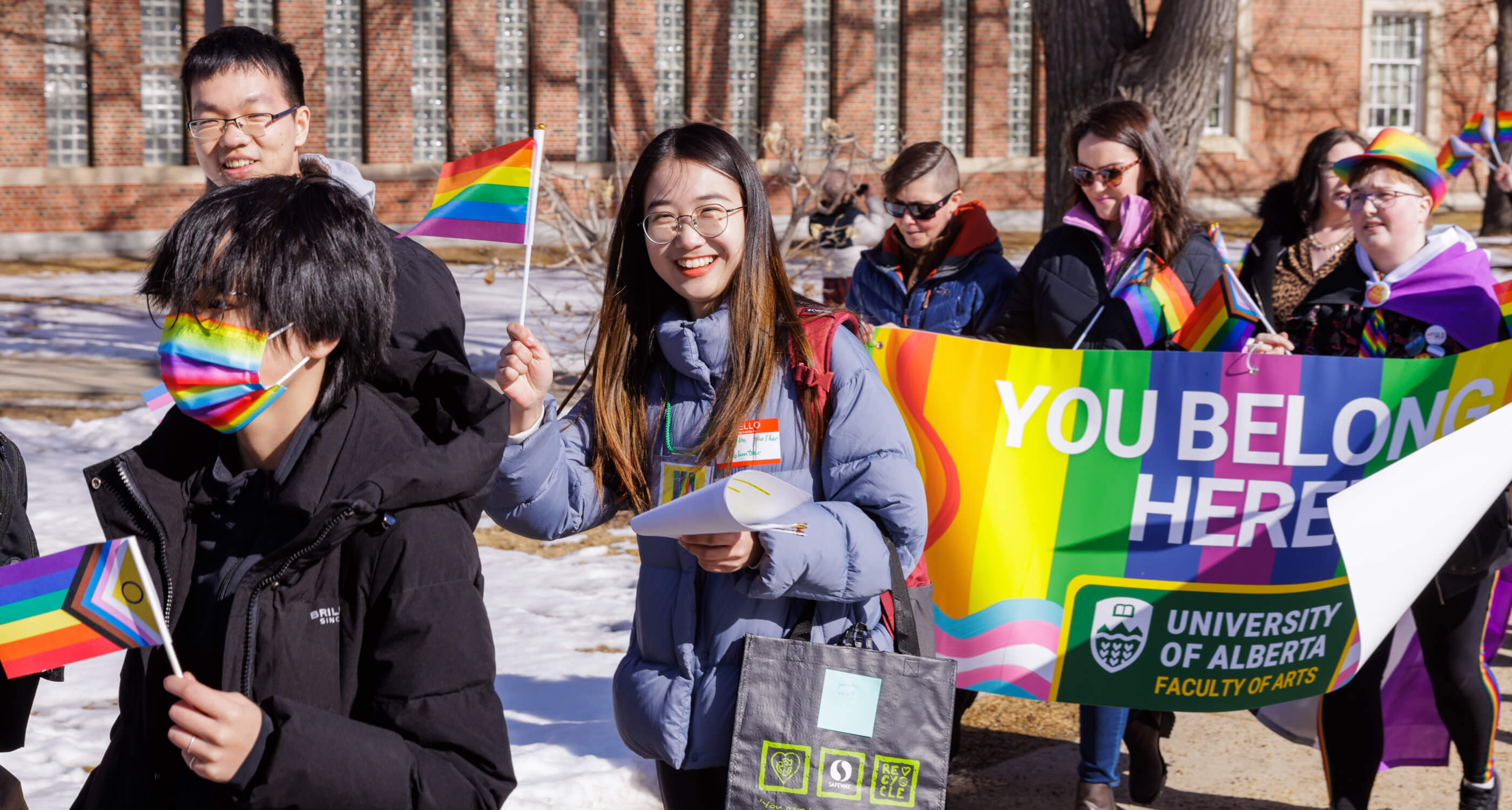 U of A students marching at Pride Parade with rainbow flags